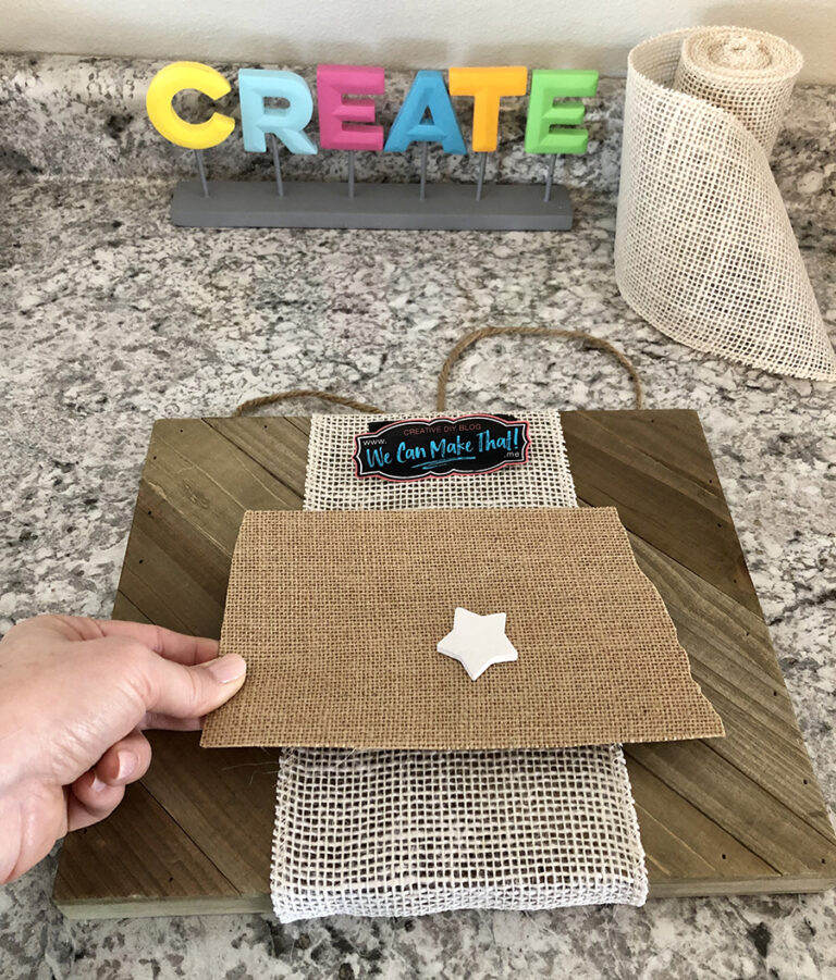 State sign cut from burlap held by a hand.