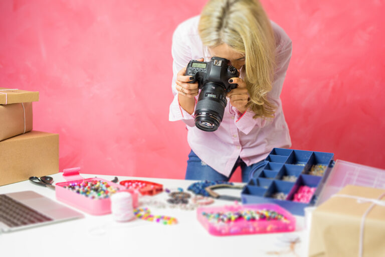 A woman taking a photo of craft items using a DSLR camera.