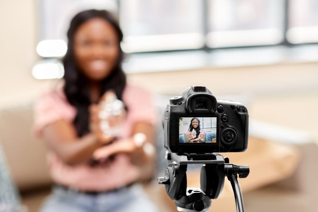 Lady in pink shirt, behind camera showing a product.