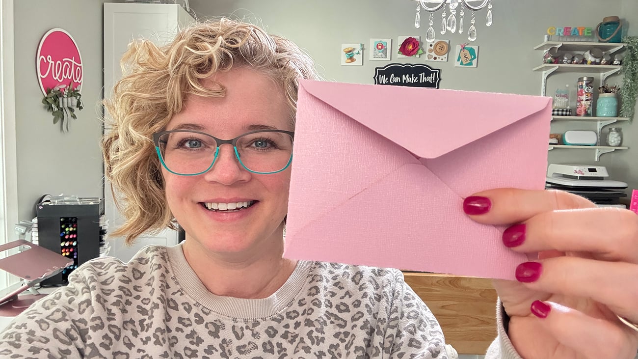 Chelly holding pink envelope she cut with her Cricut.