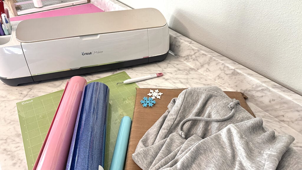 Vinyl, Cricut Maker, pressing pillow with small Cricut heatpress and gray sweatshirt.