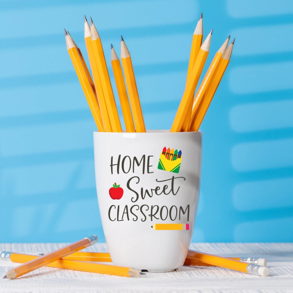 White cup as a pencil holder with teacher SVG idea, on a blue background.