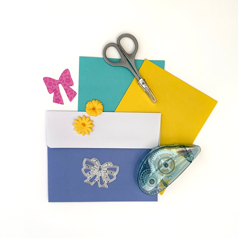 Colorful cards on white background with tape runner, scissors and supplies.