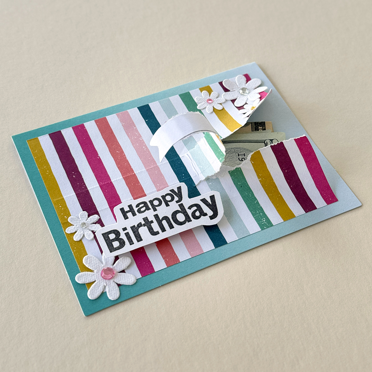 Handmade rainbow paper card with torn tab to show money.