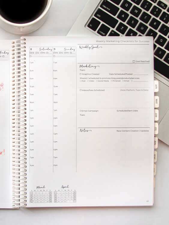 Planner open on white home office desk with laptop and coffee.
