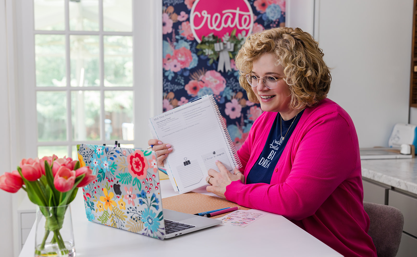 Lady at desk with small business planner teaching to a laptop.