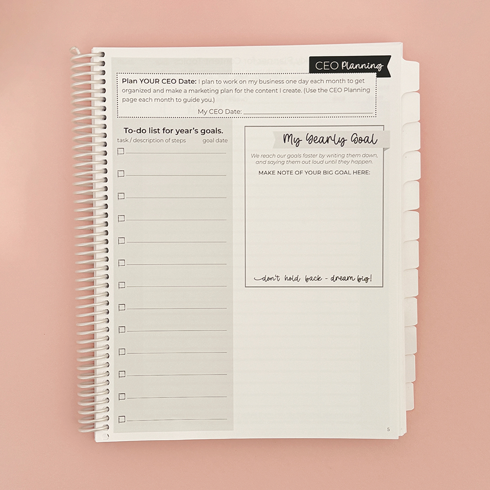 Small business planner open on pink desk.