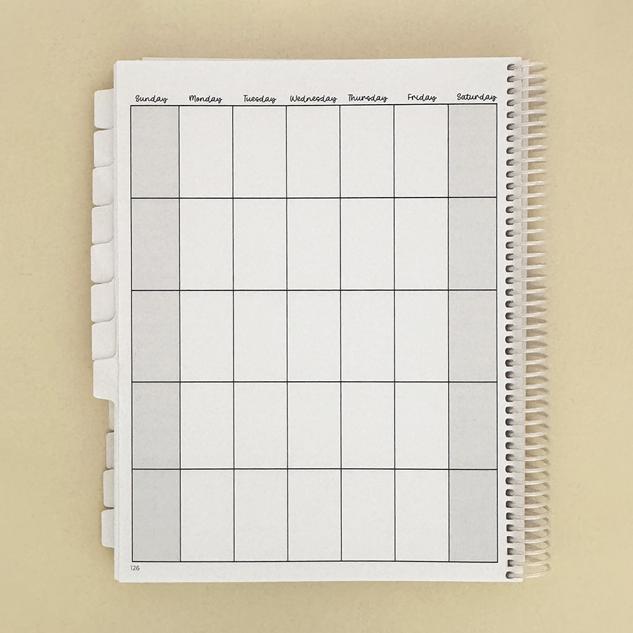 Small business planner on tan, open to monthly view.